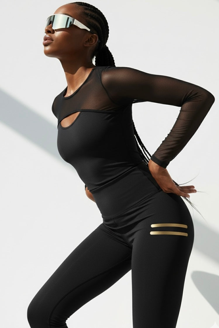 Zurückgelehnt im Shirt. Die schwarzen Leggings haben zwei kurze Goldstreifen am Oberschenkel.