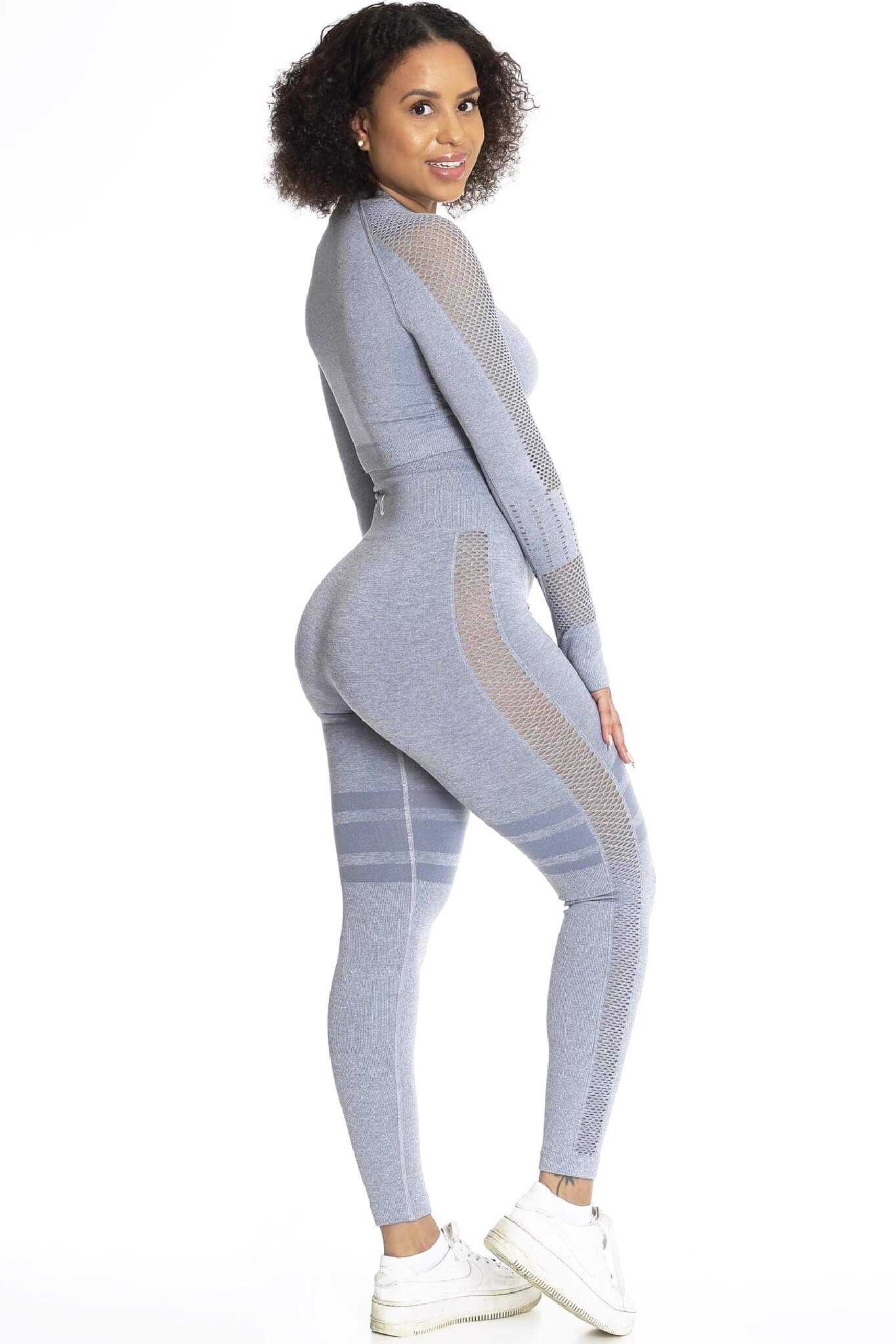 Modellen ser över axeln i grå tights och matchande tröja, med vita sneakers.