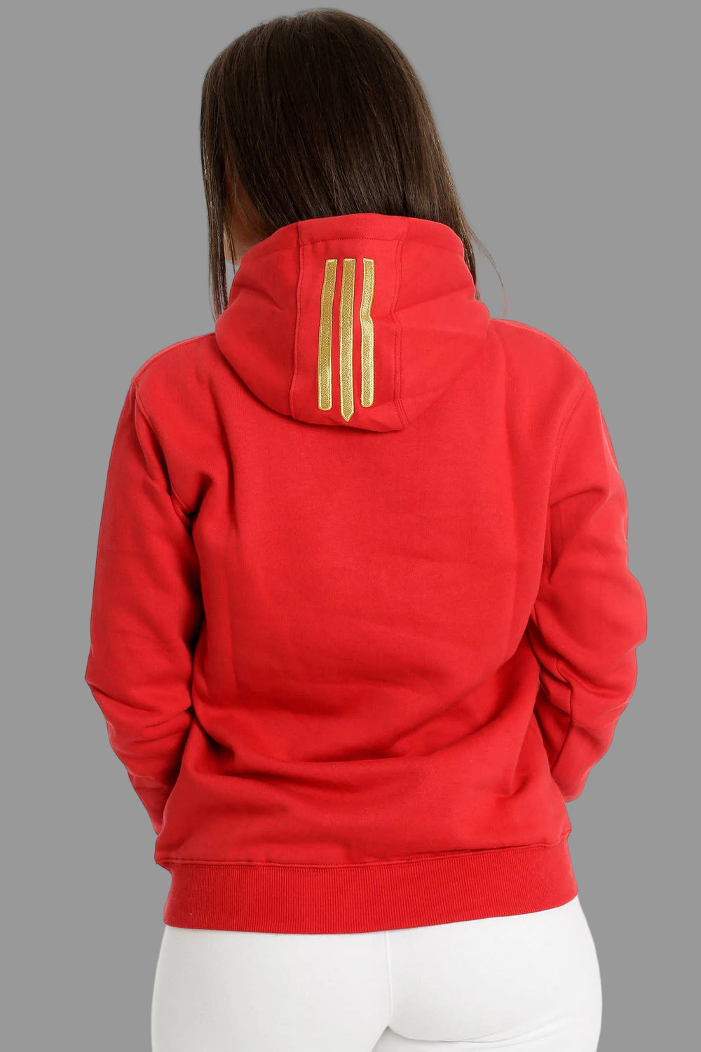 Rückseite des roten Hoodies mit drei goldfarbenen Streifen auf der Kapuze. Das Model trägt eine weiße Hose.