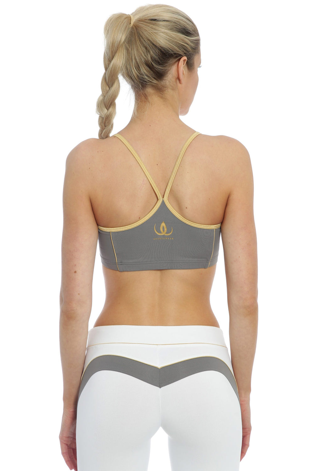 Schmale goldgefasste Träger treffen sich in einem Y auf dem Rücken des grauen Tops, zu weißen Leggings.