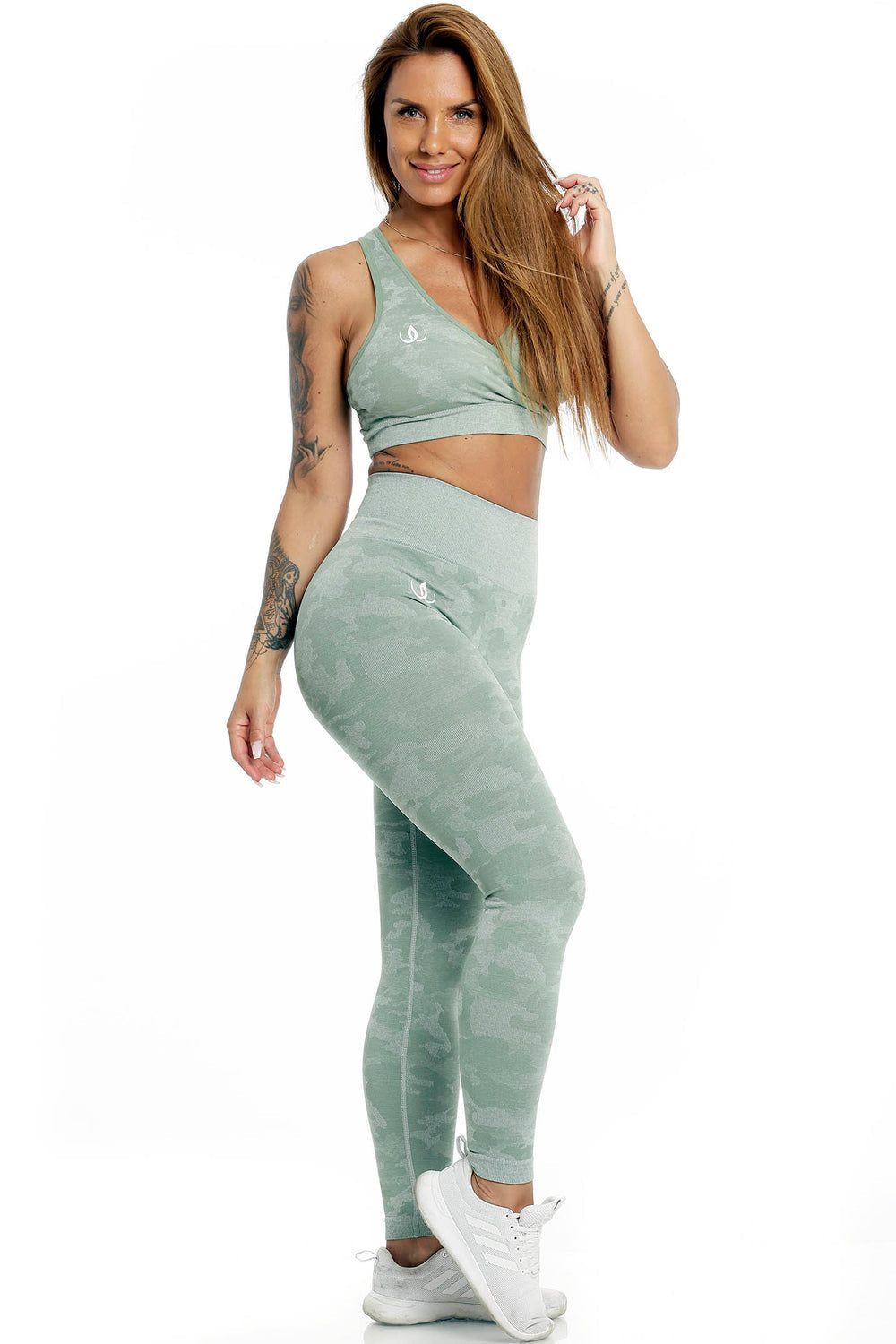 Das Model steht im mintgrünen Top und in Leggings mit Camouflage-Muster, getragen zu weißen Schuhen.
